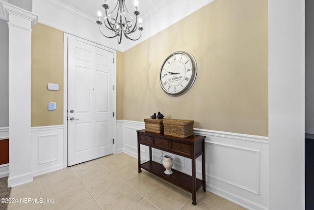 foyer featuring ornamental molding, a notable chandelier, ornate columns, and light tile patterned floors