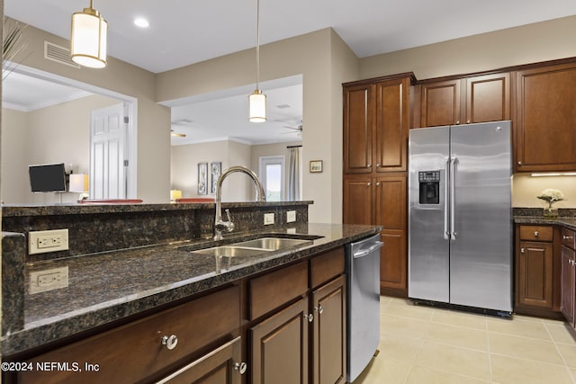 kitchen with sink, hanging light fixtures, stainless steel appliances, and dark stone counters