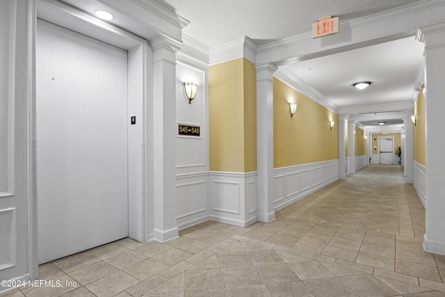 corridor with decorative columns, ornamental molding, light tile patterned floors, and elevator