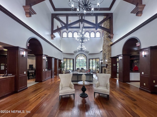 living room with a towering ceiling, hardwood / wood-style flooring, a chandelier, and decorative columns