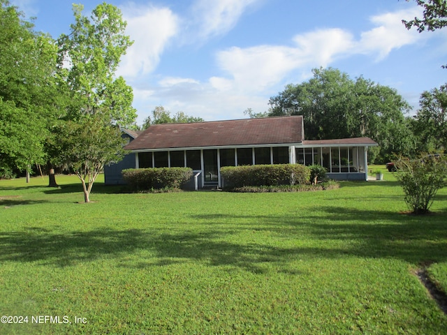 rear view of property with a yard and a sunroom