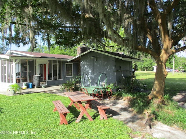 rear view of house featuring a lawn and a sunroom