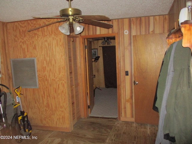 interior space featuring a textured ceiling, wood walls, and ceiling fan