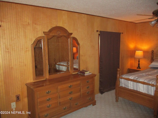 carpeted bedroom with ceiling fan, wooden walls, and a textured ceiling