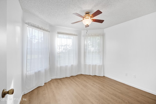 unfurnished room with ceiling fan, a textured ceiling, and light wood-type flooring