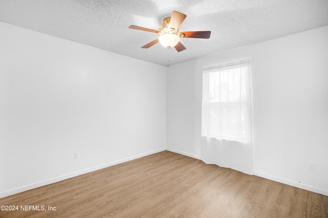 empty room featuring a textured ceiling, light wood-type flooring, and ceiling fan