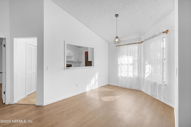 interior space with high vaulted ceiling, a textured ceiling, and light hardwood / wood-style flooring