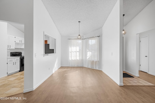 unfurnished living room with a textured ceiling, lofted ceiling, and light wood-type flooring