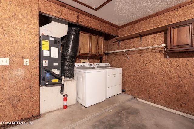 clothes washing area with cabinets, a textured ceiling, and washer and clothes dryer