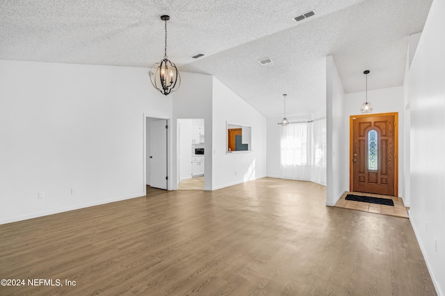 entrance foyer featuring hardwood / wood-style floors, a notable chandelier, a textured ceiling, and high vaulted ceiling