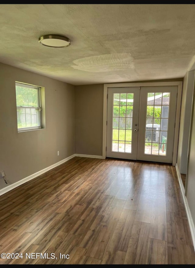 unfurnished room with french doors, a textured ceiling, and dark wood-type flooring