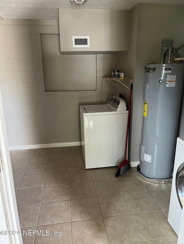 laundry room with a textured ceiling, water heater, washer / clothes dryer, and light tile patterned floors