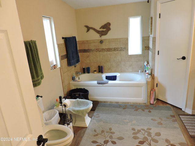 bathroom with a washtub, hardwood / wood-style floors, and toilet