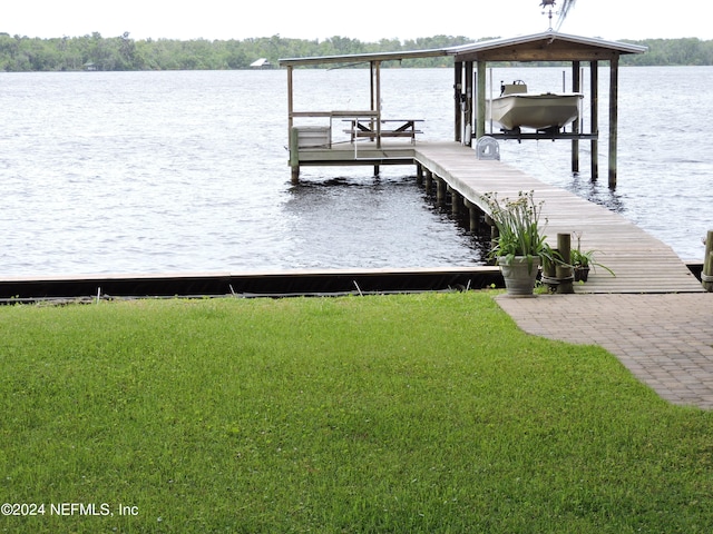 view of dock with a yard and a water view