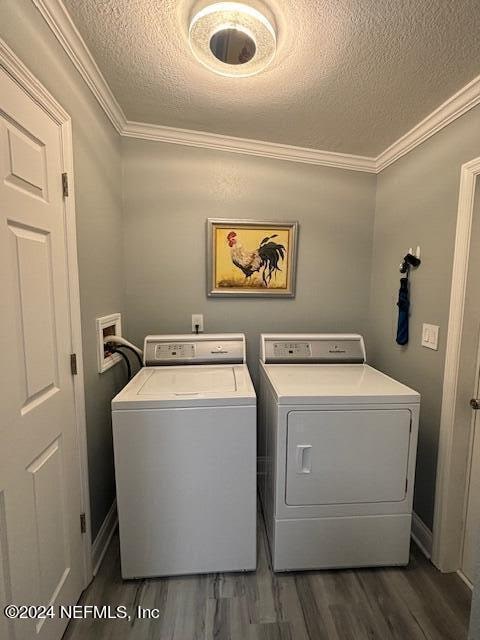 laundry area featuring ornamental molding, independent washer and dryer, and dark wood-type flooring