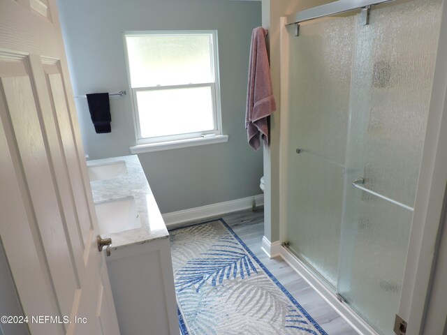 bathroom with double vanity, an enclosed shower, toilet, and hardwood / wood-style flooring