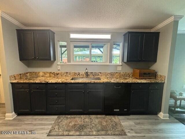 kitchen featuring crown molding, light stone counters, sink, and light wood-type flooring