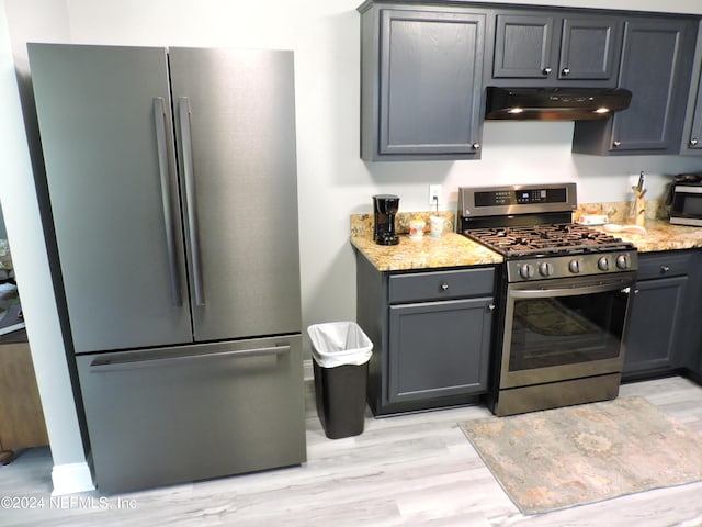 kitchen featuring appliances with stainless steel finishes, light hardwood / wood-style flooring, fume extractor, and light stone countertops