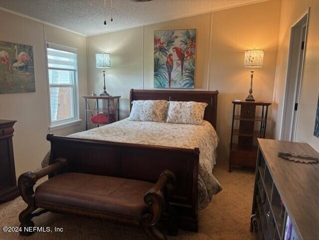 bedroom featuring light carpet, crown molding, and a textured ceiling