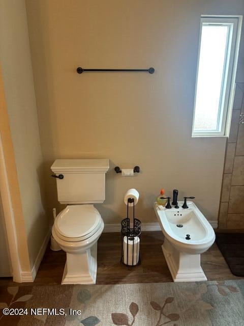 bathroom featuring wood-type flooring, toilet, and a bidet