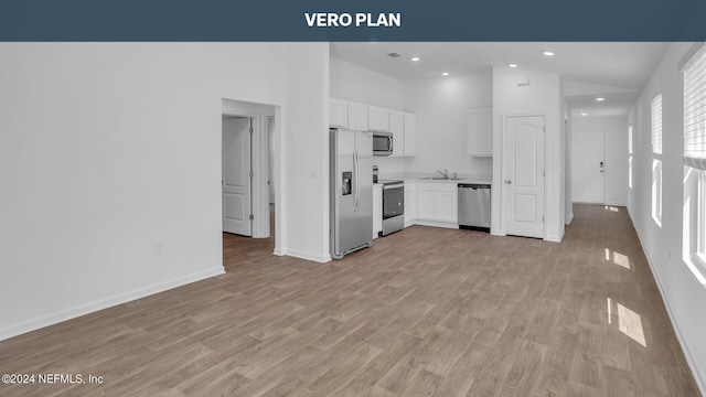 kitchen with high vaulted ceiling, appliances with stainless steel finishes, hardwood / wood-style flooring, white cabinetry, and sink