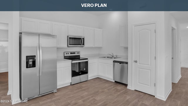 kitchen featuring appliances with stainless steel finishes, sink, light wood-type flooring, and white cabinetry