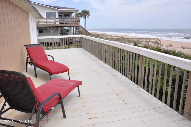 wooden deck featuring a water view and a beach view