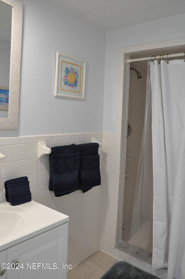 bathroom with a shower with curtain, tile patterned floors, vanity, and tile walls