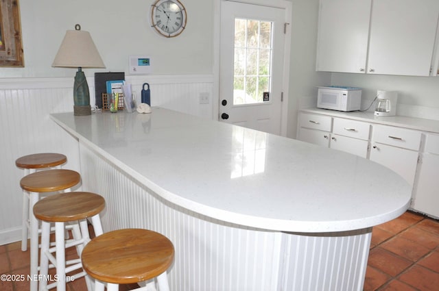 kitchen with white cabinetry, a breakfast bar area, tile patterned floors, and kitchen peninsula