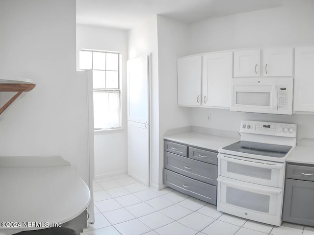 kitchen featuring gray cabinets, white cabinetry, light tile patterned flooring, and white appliances