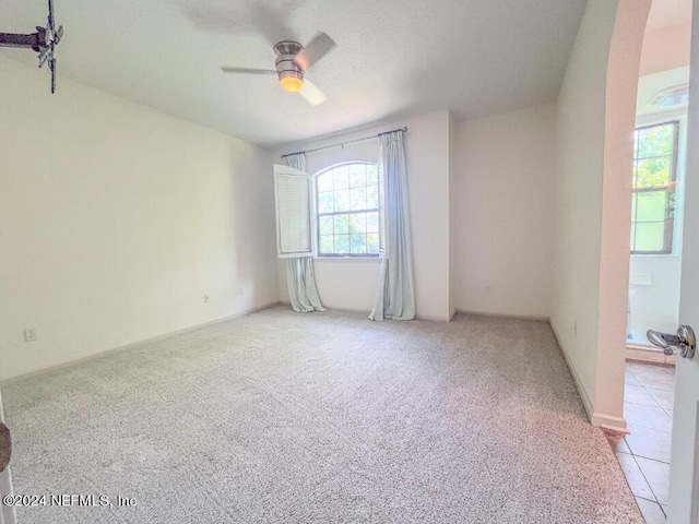 tiled empty room featuring ceiling fan