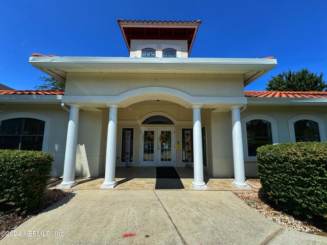 entrance to property with a porch and french doors