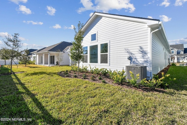 rear view of property with a lawn and cooling unit