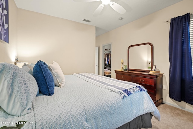 bedroom with ceiling fan, light colored carpet, a closet, and a spacious closet