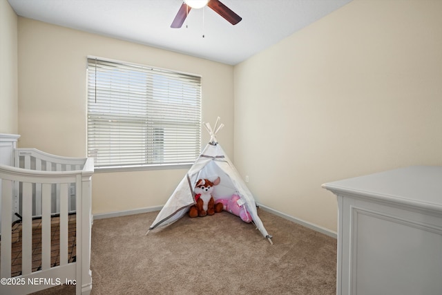 carpeted bedroom featuring ceiling fan and a crib