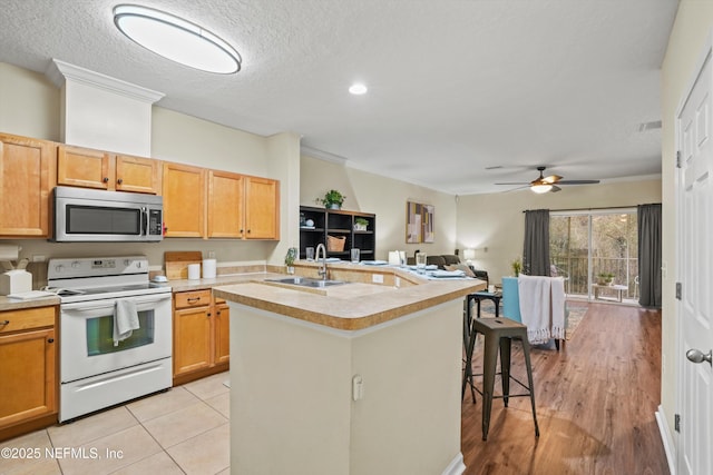 kitchen featuring white range with electric cooktop, sink, a kitchen island with sink, and a textured ceiling