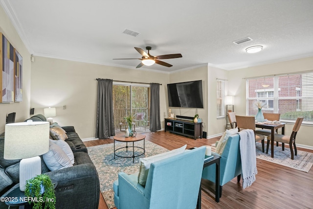 living room with ceiling fan, crown molding, a textured ceiling, and wood-type flooring