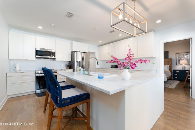 kitchen with white cabinets, light hardwood / wood-style floors, and appliances with stainless steel finishes