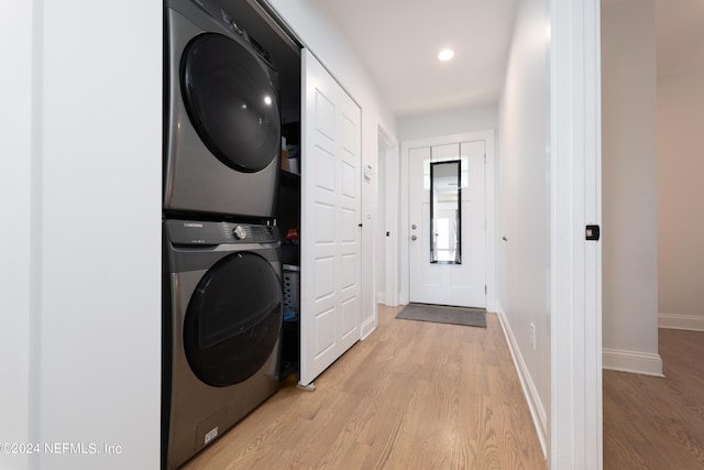 clothes washing area featuring light hardwood / wood-style floors and stacked washer / dryer