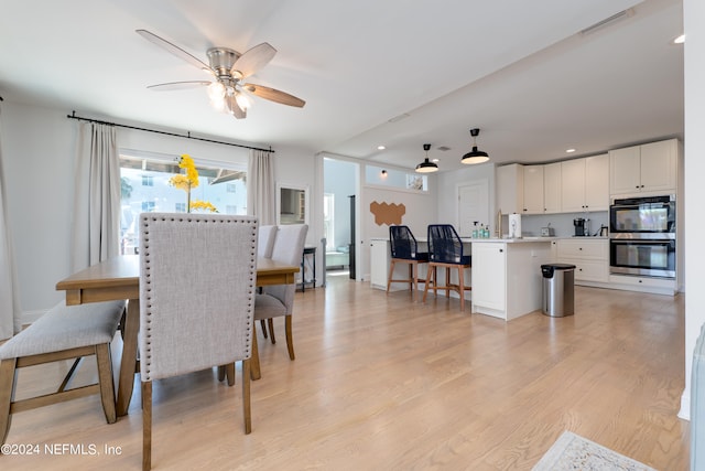 dining area with light hardwood / wood-style flooring and ceiling fan