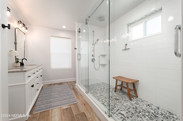 bathroom with wood-type flooring, a shower with shower door, and vanity