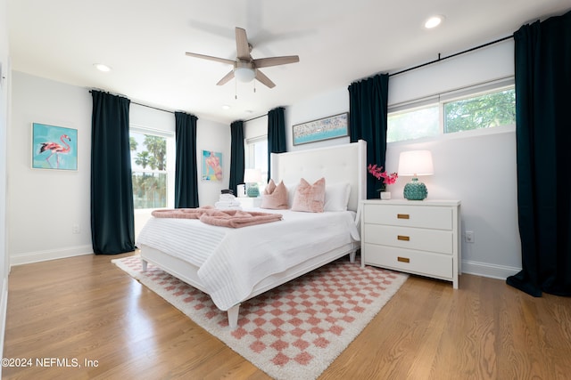 bedroom featuring light wood-type flooring, ceiling fan, and multiple windows