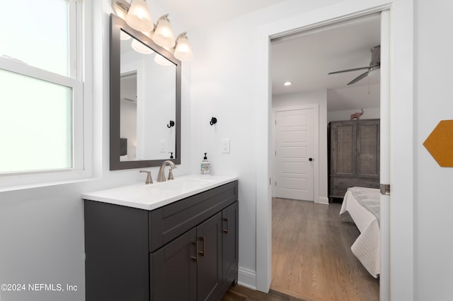 bathroom with ceiling fan, vanity with extensive cabinet space, and hardwood / wood-style flooring