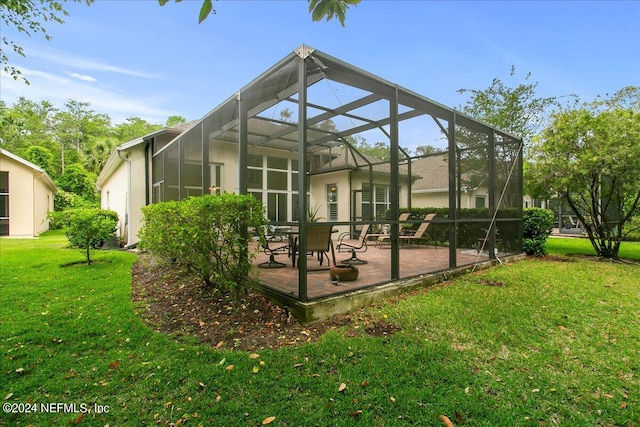 back of house featuring glass enclosure, a patio area, and a yard