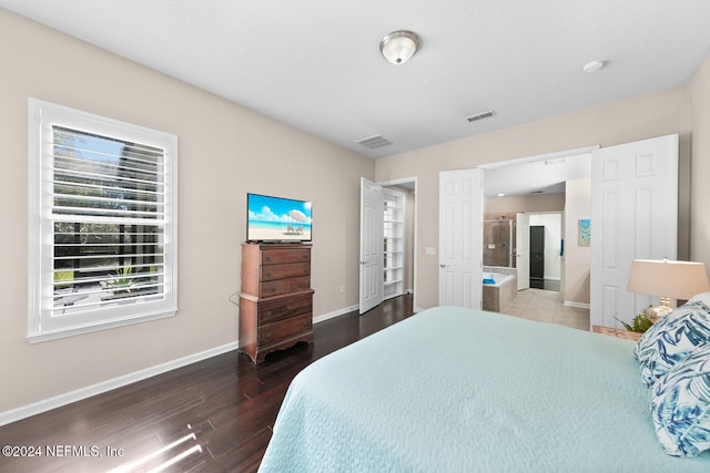 bedroom with ensuite bath and dark wood-type flooring