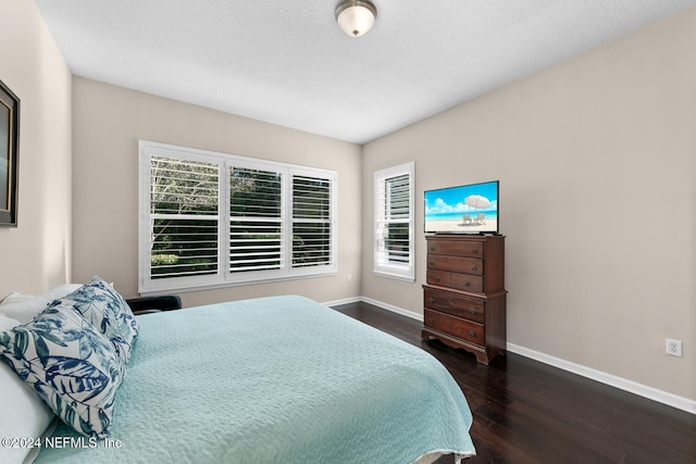 bedroom featuring a textured ceiling, multiple windows, and dark wood-type flooring