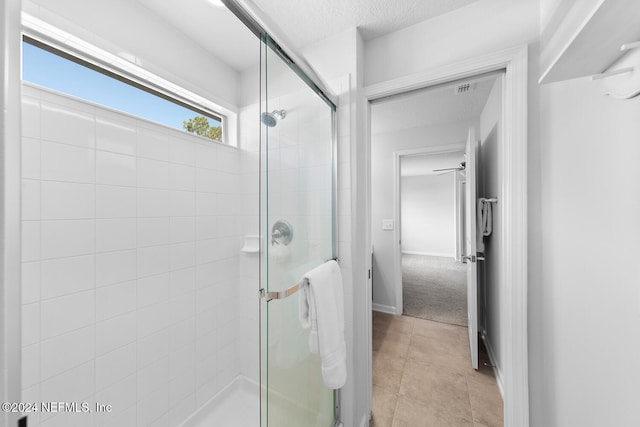 bathroom with a textured ceiling, tile patterned floors, an enclosed shower, and ceiling fan