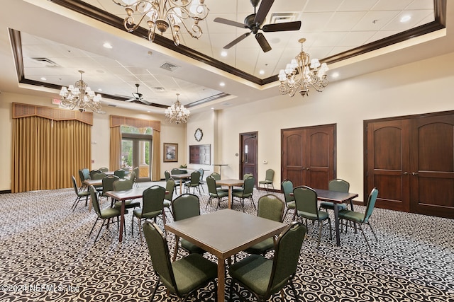 carpeted dining space with ceiling fan with notable chandelier, a raised ceiling, ornamental molding, and a towering ceiling