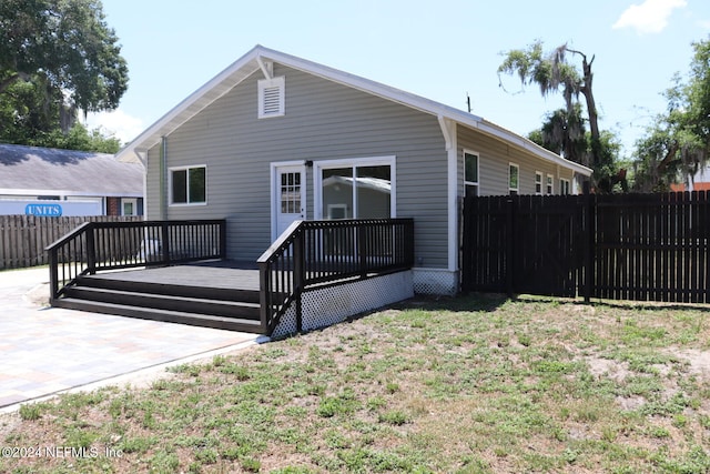 back of house with a wooden deck and a lawn