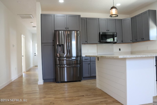 kitchen featuring gray cabinetry, light wood-type flooring, decorative light fixtures, stainless steel appliances, and light stone countertops